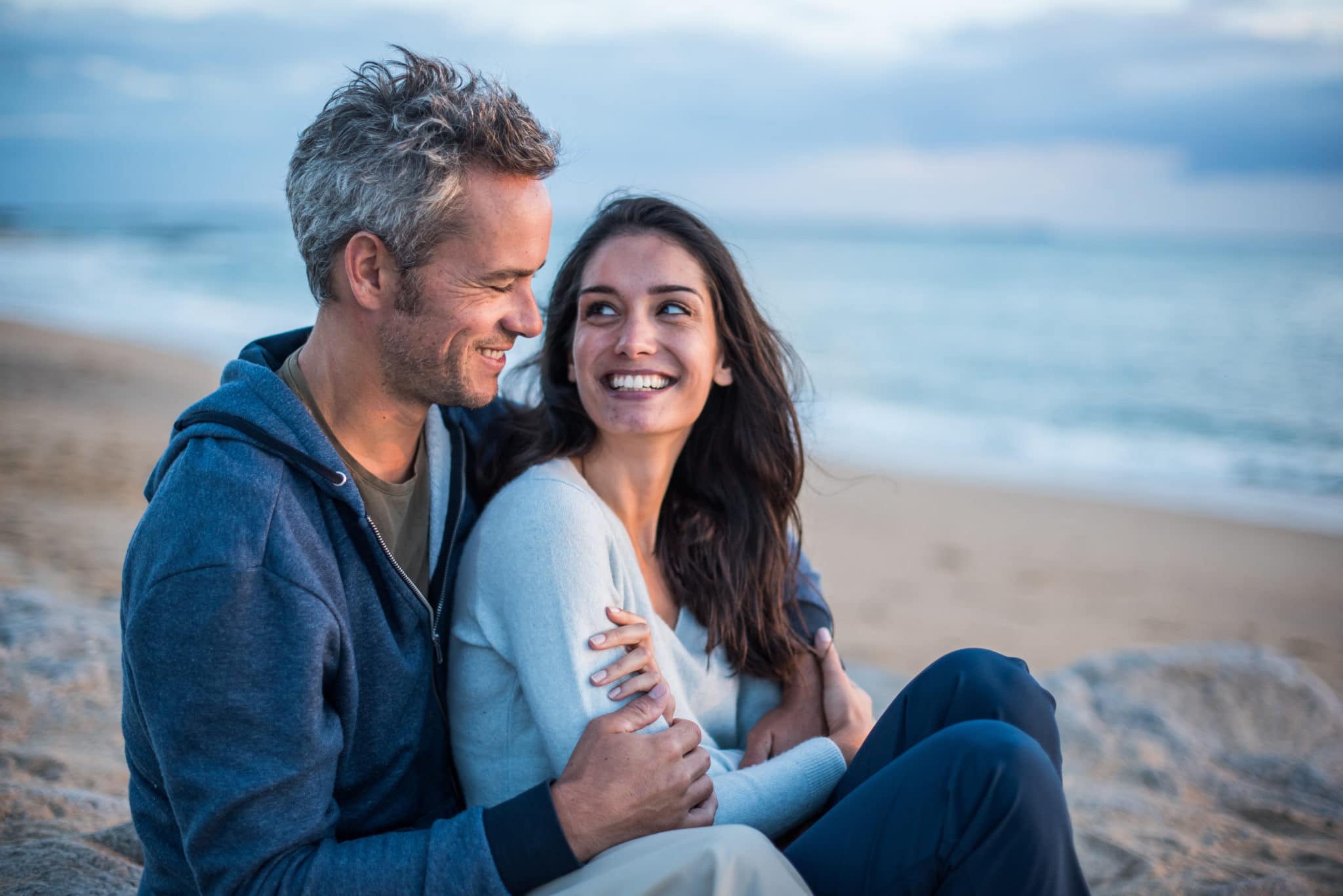 Beautiful couple sitting at the beach watching the sunset